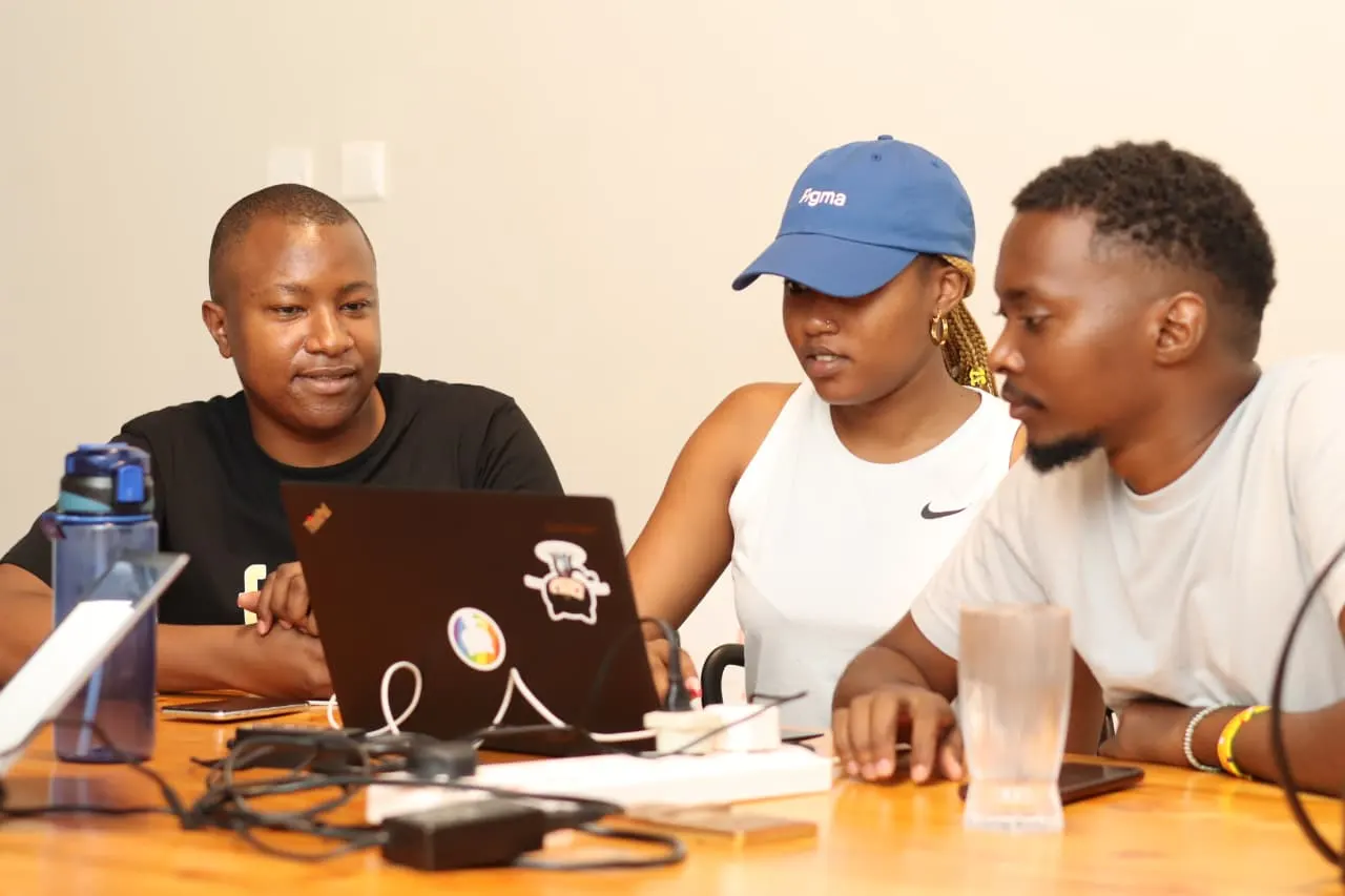 Three members of the Mellow crew gathered around a sticker-covered laptop, deep in an edit