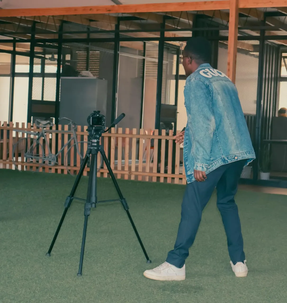 Ian Asena, back turned to the camera, walking toward his tripod in a bright studio space