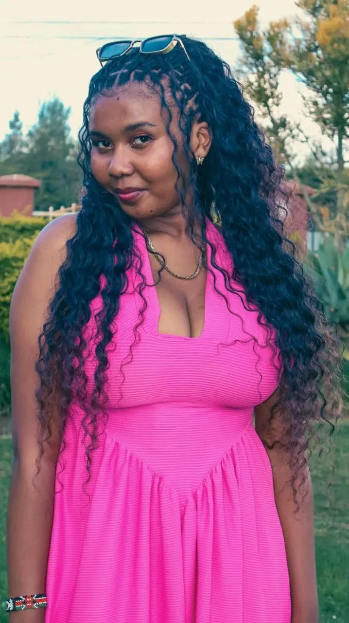 A woman in a pink halter dress photographed in soft garden light, sunglasses resting in her hair